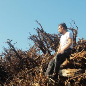 autor siedzący na stosie wyrwanych korzeni drzew